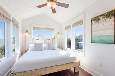 a bedroom with a bed with windows and a ceiling fan at Tucked Away in Inlet Beach