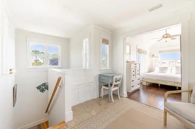 a white bedroom with a bed and a desk at Tucked Away in Inlet Beach