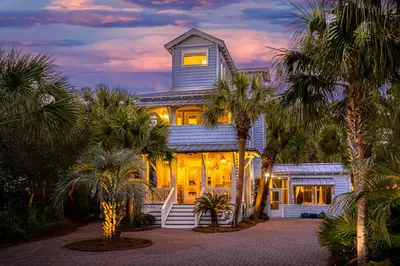 a house with palm trees in front of it at Tucked Away in Inlet Beach