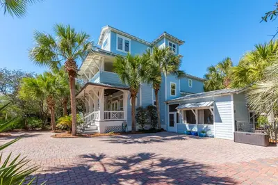 a blue house with palm trees in front of it at Tucked Away in Inlet Beach