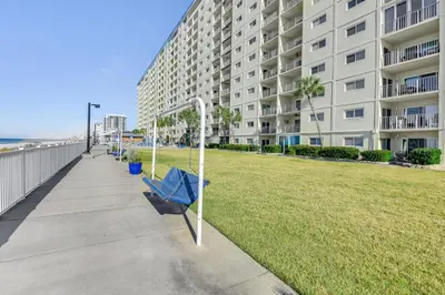 a blue bench on a sidewalk next to a large building at Regency Towers PCB Condo Beach Access and 2 Pools in Panama City Beach