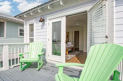 two green chairs on a porch with a table at Mi CaSEAta in Rosemary Beach