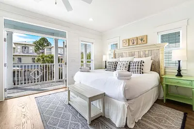 a white bedroom with a bed and a balcony at Mi CaSEAta in Rosemary Beach
