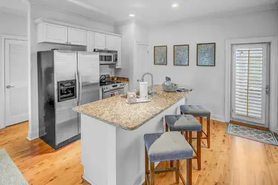 a kitchen with a refrigerator and a counter with stools at Surf on Turf -Whole House in Rosemary Beach