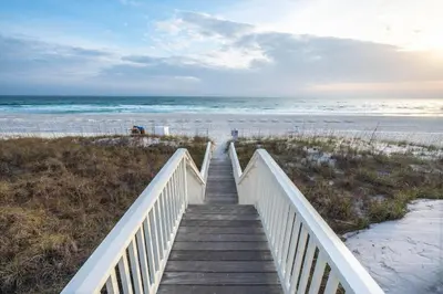 a wooden staircase leading to a beach with the ocean at Grand Tortuga Squirt in Panama City Beach