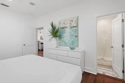 a white bedroom with a bed and a painting on the wall at The Magnolia Mermaid in Panama City Beach
