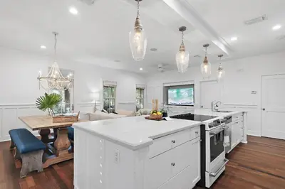 a kitchen with white cabinets and a table in a room at The Magnolia Mermaid in Panama City Beach