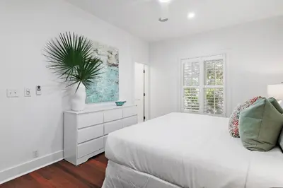 a white bedroom with a white bed and a plant at The Magnolia Mermaid in Panama City Beach