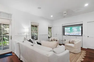 a living room with white furniture and a flat screen tv at The Magnolia Mermaid in Panama City Beach