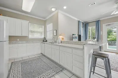 a kitchen with white cabinets and a stool at Ten Grand in Santa Rosa Beach