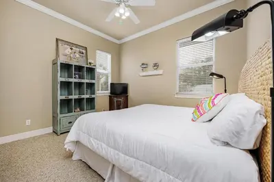 a bedroom with a white bed and a book shelf at Ten Grand in Santa Rosa Beach