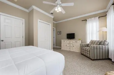 a bedroom with a large white bed and a chair at Ten Grand in Santa Rosa Beach