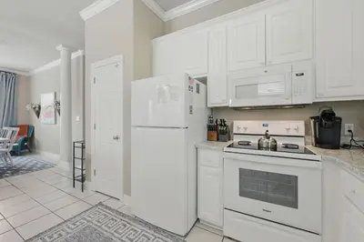 a kitchen with white cabinets and a white refrigerator at Ten Grand in Santa Rosa Beach