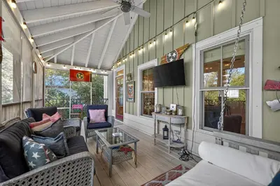 a screened in porch with a couch and a tv at Tennessee by the Sea in Inlet Beach