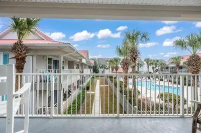 a balcony with a view of a pool and palm trees at Rollin Tides in Santa Rosa Beach