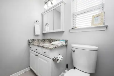 a white bathroom with a toilet and a sink at Rollin Tides in Santa Rosa Beach