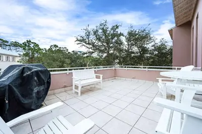 a patio with white chairs and tables on a balcony at Grand Tortuga Crush in Panama City Beach
