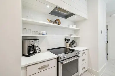 a kitchen with white cabinets and a stove top oven at Summer Breeze by 30A Escapes in Rosemary Beach