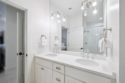 a white bathroom with two sinks and a mirror at Summer Breeze by 30A Escapes in Rosemary Beach