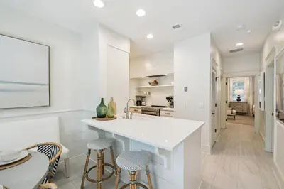 a kitchen with a white counter and stools at Summer Breeze by 30A Escapes in Rosemary Beach