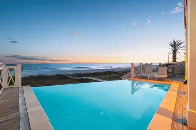 a swimming pool with a view of the ocean at The Sand Castle by 30A Escapes in Panama City Beach
