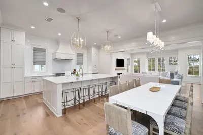 a kitchen with white cabinets and a table and chairs at Paralia 30A in Seagrove Beach