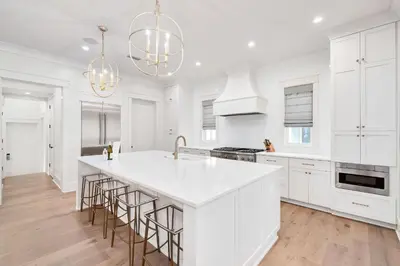 a kitchen with white cabinets and a large island with bar stools at Paralia 30A in Seagrove Beach