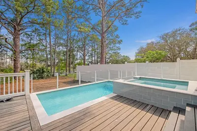a swimming pool on a wooden deck next to a fence at Paralia 30A in Seagrove Beach