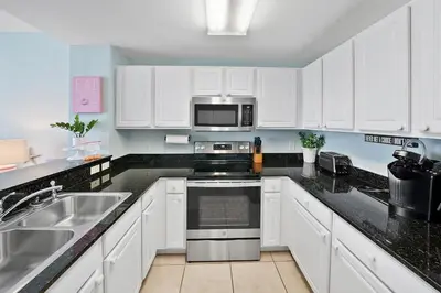 a kitchen with white cabinets and a stove top oven at Calypso 1007E in Panama City Beach