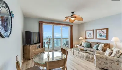 a living room with a couch and a television and a table at Calypso 1607E in Panama City Beach