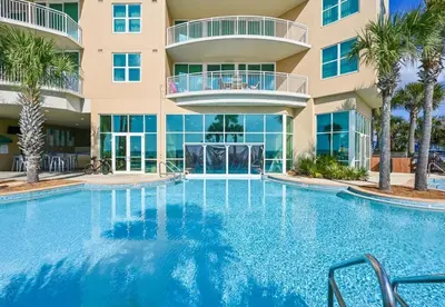 a swimming pool in front of a building with palm trees at Aqua 408 in Panama City Beach