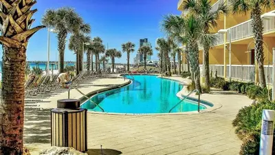 a swimming pool with palm trees next to a building at Calypso 2107W in Panama City Beach