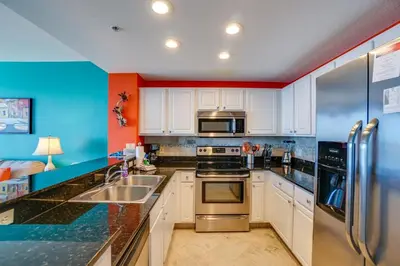 a kitchen with white cabinets and chrome appliances at Calypso 2107W in Panama City Beach