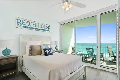 a bedroom with a bed and a balcony with the ocean at Aqua 603 in Panama City Beach