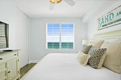 a white bedroom with a bed and a window at Aqua 603 in Panama City Beach