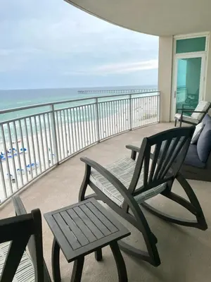 two chairs and a bench on a balcony with the ocean at Aqua 603 in Panama City Beach