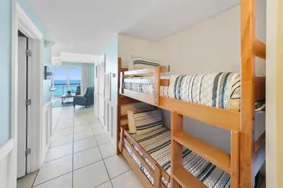 a bedroom with two bunk beds and a living room at Calypso 803W in Panama City Beach