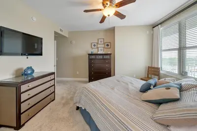 a bedroom with a bed with a ceiling fan and a dresser at 609 Aqua in Panama City Beach