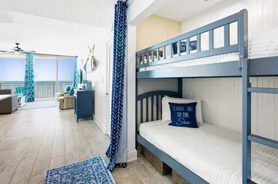 a bedroom with bunk beds and a living room at Aqua 705 in Panama City Beach