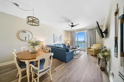 a living room with a table and a blue couch at Calypso 908W Stunning condo, beach front, and immaculate in Panama City Beach