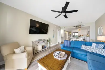 a living room with a blue couch and a ceiling fan at Calypso 908W Stunning condo, beach front, and immaculate in Panama City Beach
