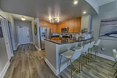 a kitchen with a counter and chairs in a room at Aqua 707 in Panama City Beach