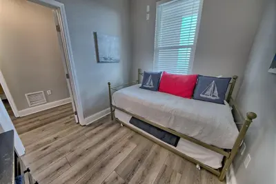 a small bedroom with a bed with red and blue pillows at Aqua 707 in Panama City Beach