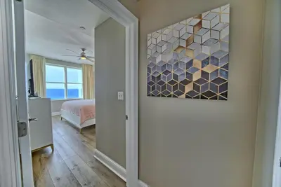 a hallway with a bedroom with a painting on the wall at Aqua 707 in Panama City Beach