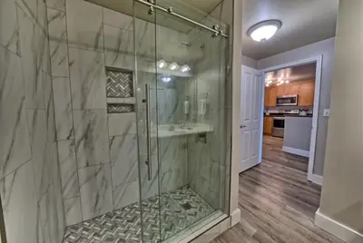 a bathroom with a glass shower with a sink at Aqua 707 in Panama City Beach