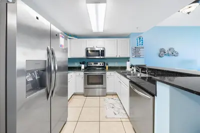 a kitchen with stainless steel appliances and blue walls at Calypso 108W Like having your private beach house! Beachfront! in Panama City Beach