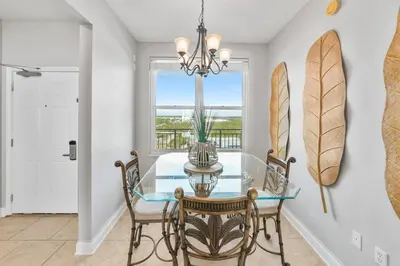 a dining room with a glass table and chairs and a window at Aqua 1003 in Panama City Beach