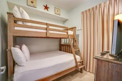 a bedroom with two bunk beds and a television at Calypso 202E Paradise at Calypso 4 chairs daily Gulf Front in Panama City Beach