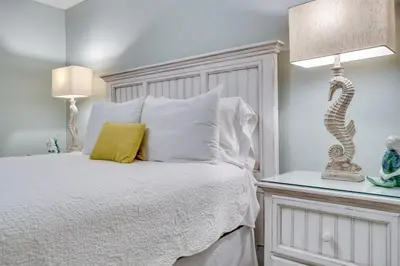 a bedroom with a white bed and two lamps at Calypso 202E Paradise at Calypso 4 chairs daily Gulf Front in Panama City Beach