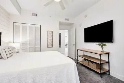 a white bedroom with a large bed and a flat screen tv at Aqua 2004 in Panama City Beach